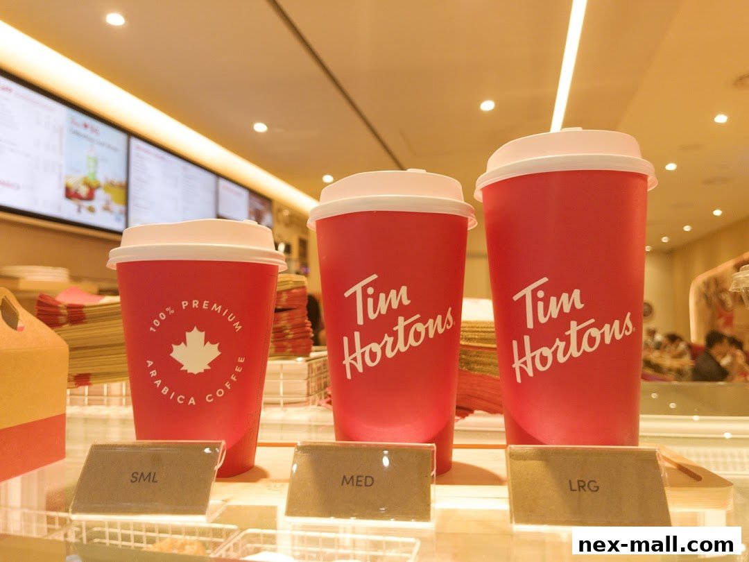 Three red Tim Hortons coffee cups of different sizes are displayed on a counter.