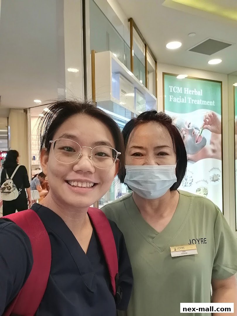 Two women smiling at the camera in front of a spa with a TCM Herbal Facial Treatment sign.