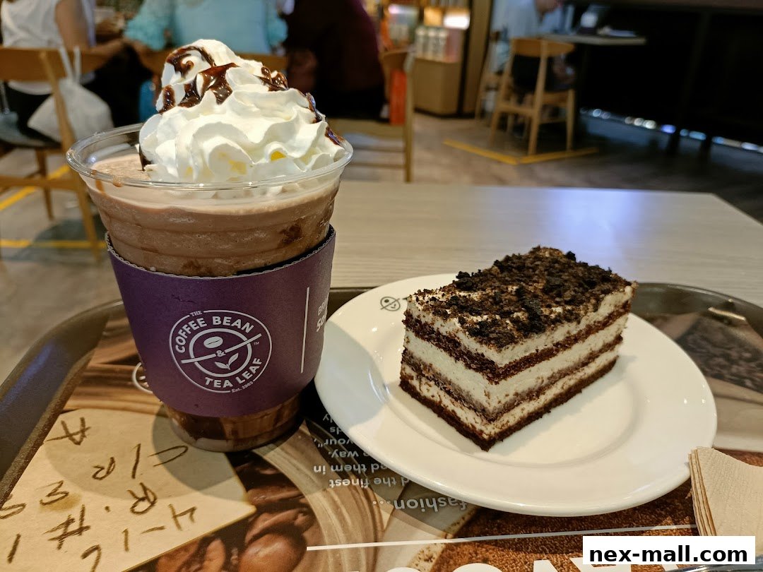 A chocolate frappe topped with whipped cream and chocolate drizzle next to a slice of layered cake.