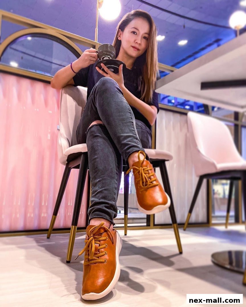 A woman sits on a chair, holding a cup and saucer, showcasing her stylish brown shoes.