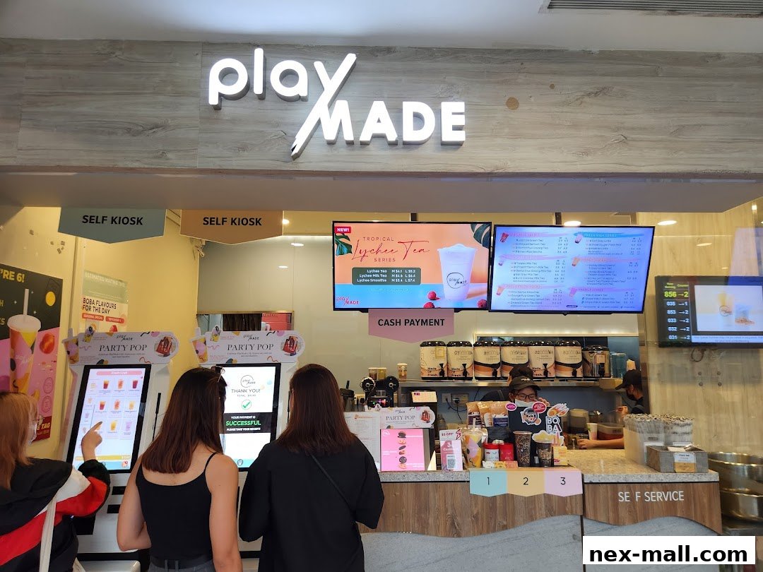 Customers ordering at self-kiosks and the counter of a PlayMade bubble tea shop.