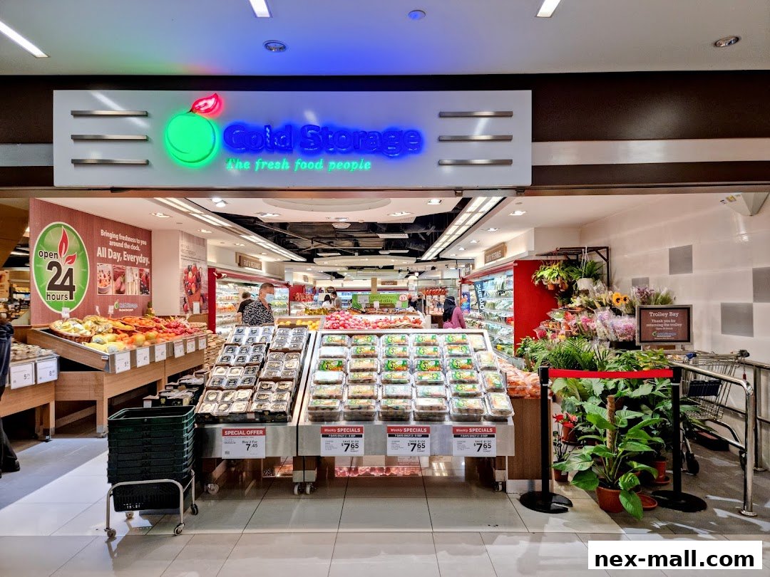 The entrance of a Cold Storage supermarket, showcasing fresh produce and floral displays.