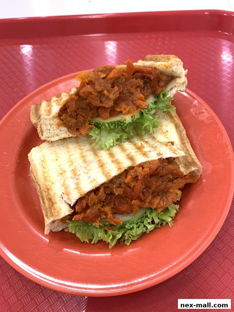 A close-up shot of a delicious kaya toast sandwich with a savory filling on a red plate.