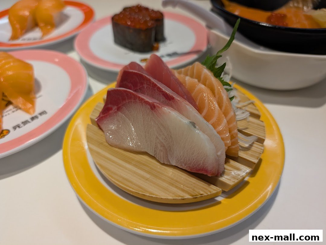 A close-up of fresh sashimi and sushi on plates at Genki Sushi NEX.