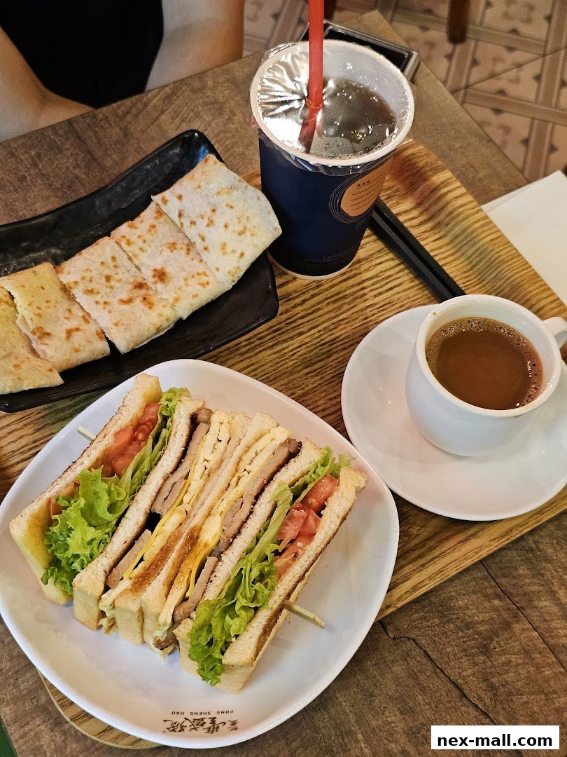 A delicious club sandwich with a side of flatbread and two drinks on a wooden table.