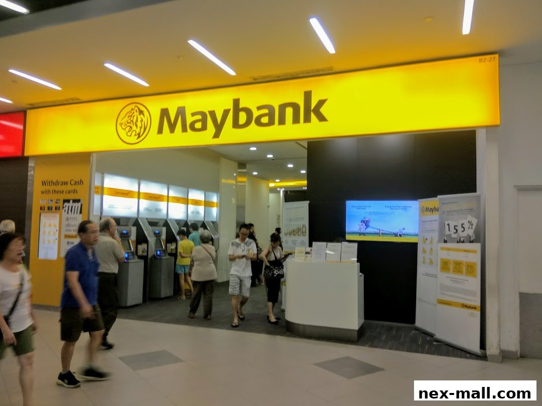 The Maybank branch entrance with ATMs and promotional displays, featuring a bright yellow sign.