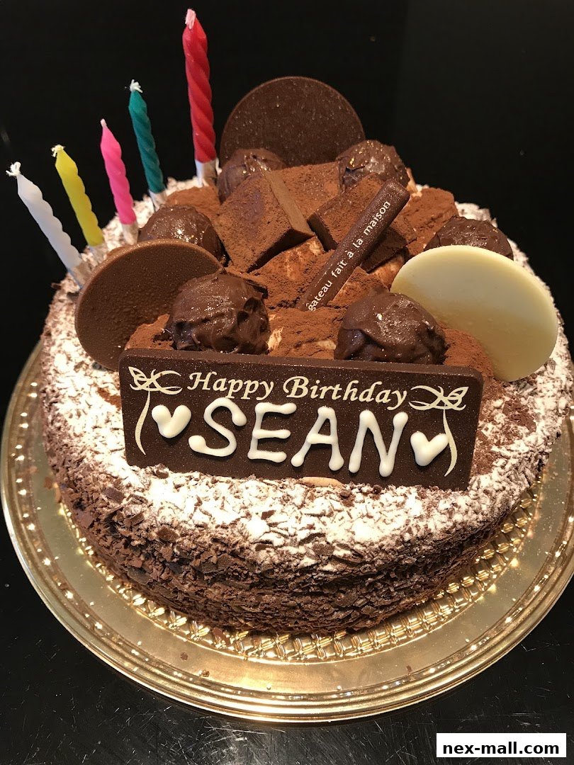 A decadent chocolate birthday cake with candles and personalized 'Happy Birthday Sean' message.