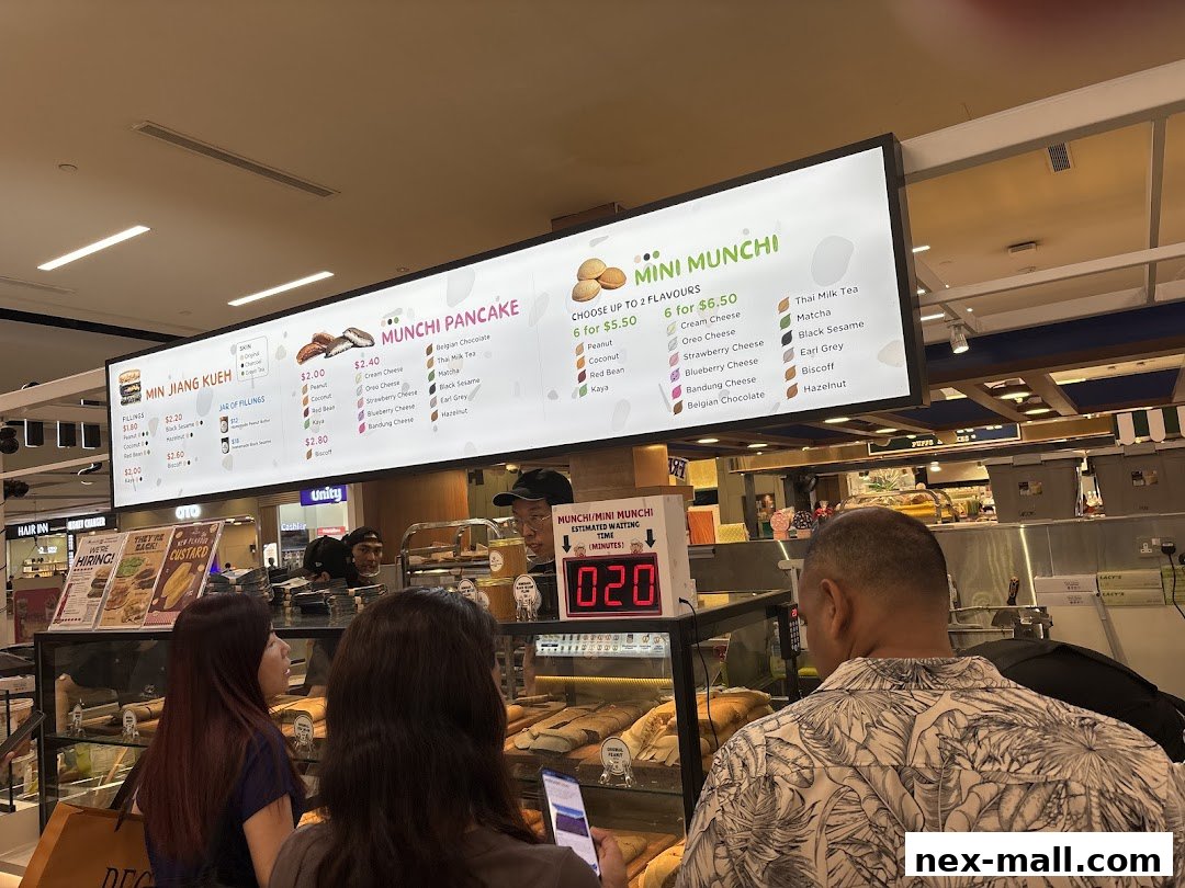A brightly lit menu board displays various pancake and kueh options with prices.