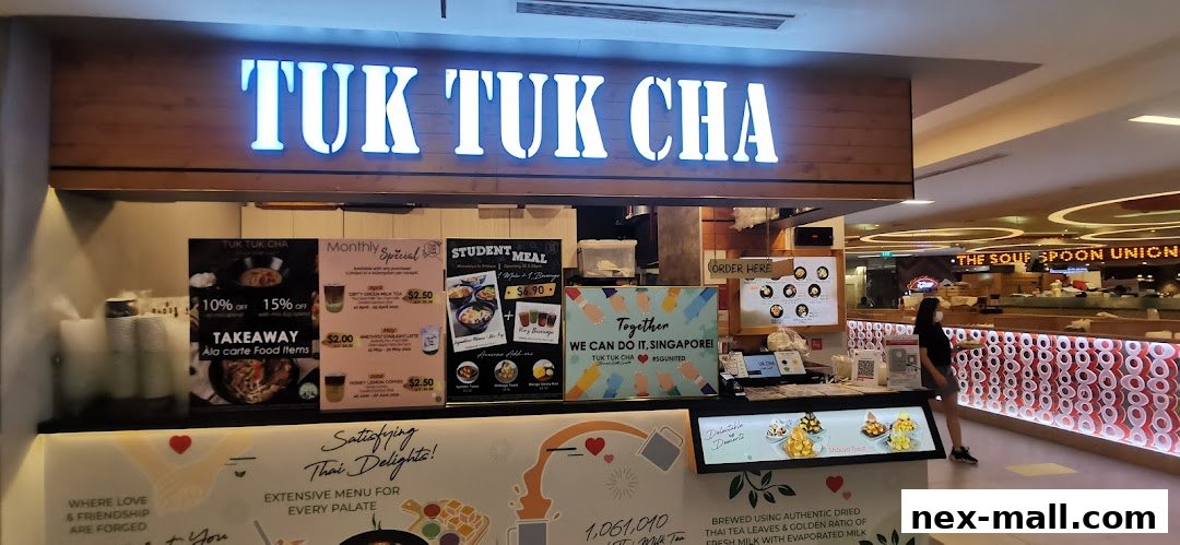 The storefront of Tuk Tuk Cha, a Thai food and drink establishment, with promotional posters and a menu displayed.