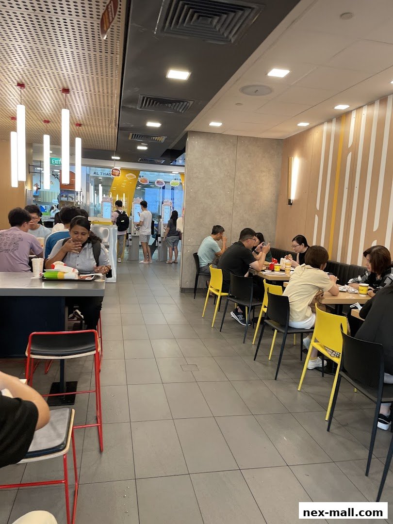 People dining and ordering at a busy McDonald's restaurant with self-order kiosks.
