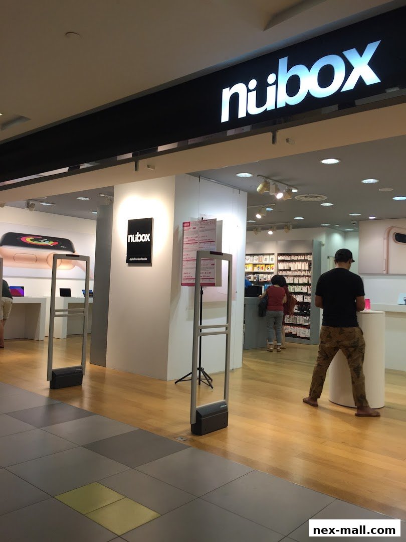 The entrance of a modern electronics store with a prominent 'nubox' logo and displays of Apple products.