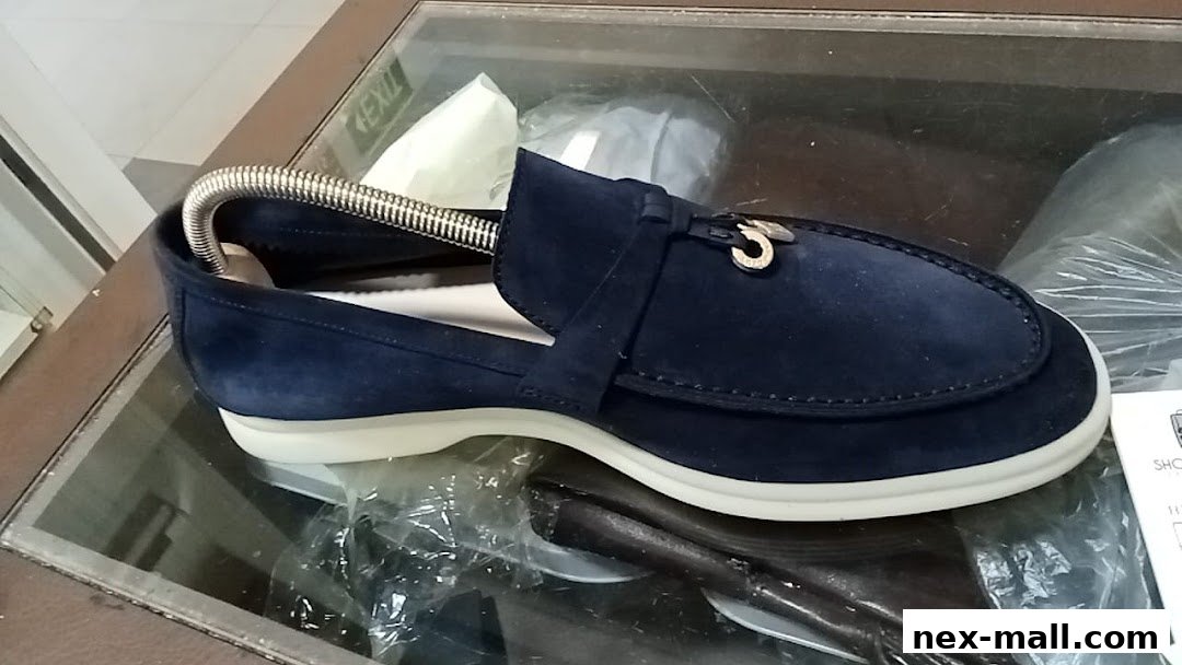 A close-up view of a stylish navy blue suede loafer with a metal accent.