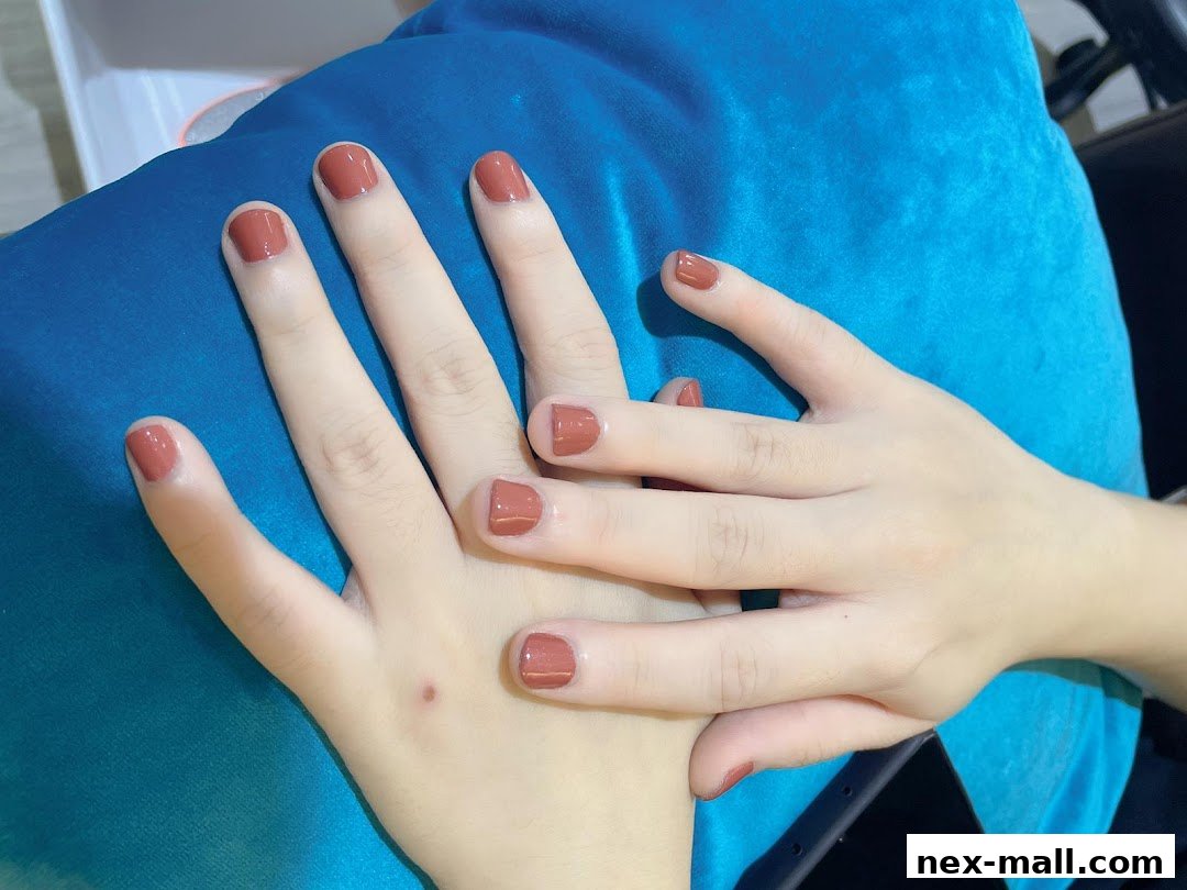 Close-up of hands with perfectly manicured nails painted in a warm, earthy tone.