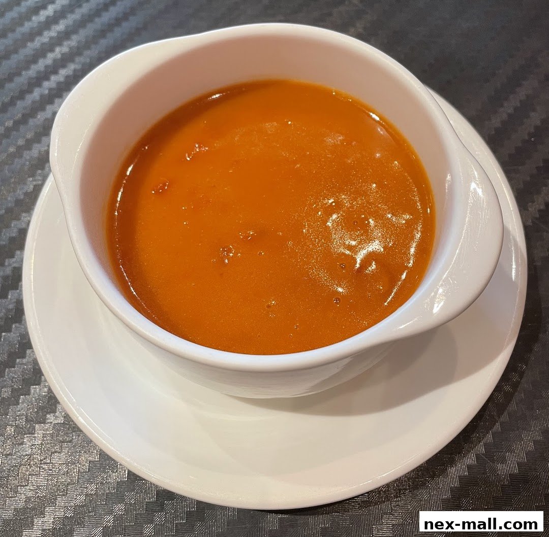 A close-up shot of a steaming bowl of rich, orange curry soup.
