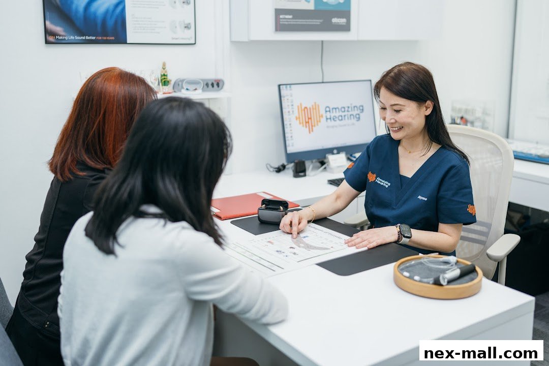 A hearing specialist consults with two clients at a desk, discussing hearing health.