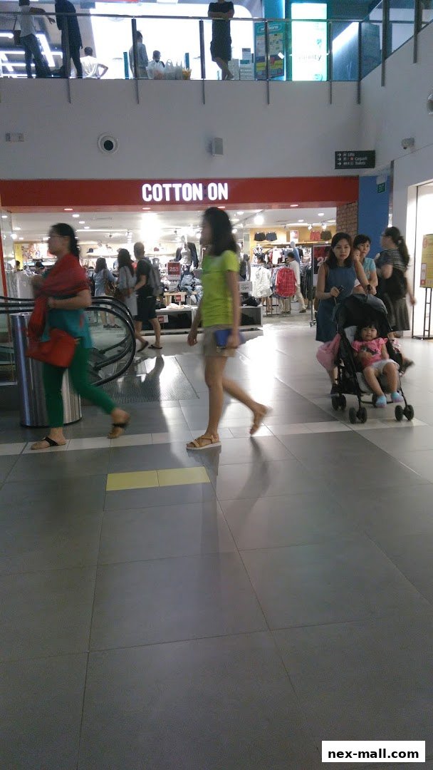 People walking past the Cotton On store entrance in a shopping mall.