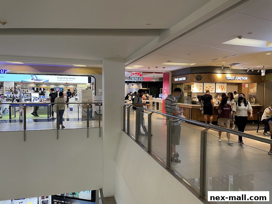 People walking in a mall with shops like Singtel and Toast Junction visible.