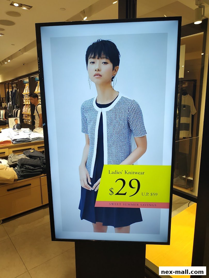 A digital display shows a model wearing knitwear with a price tag for summer savings.