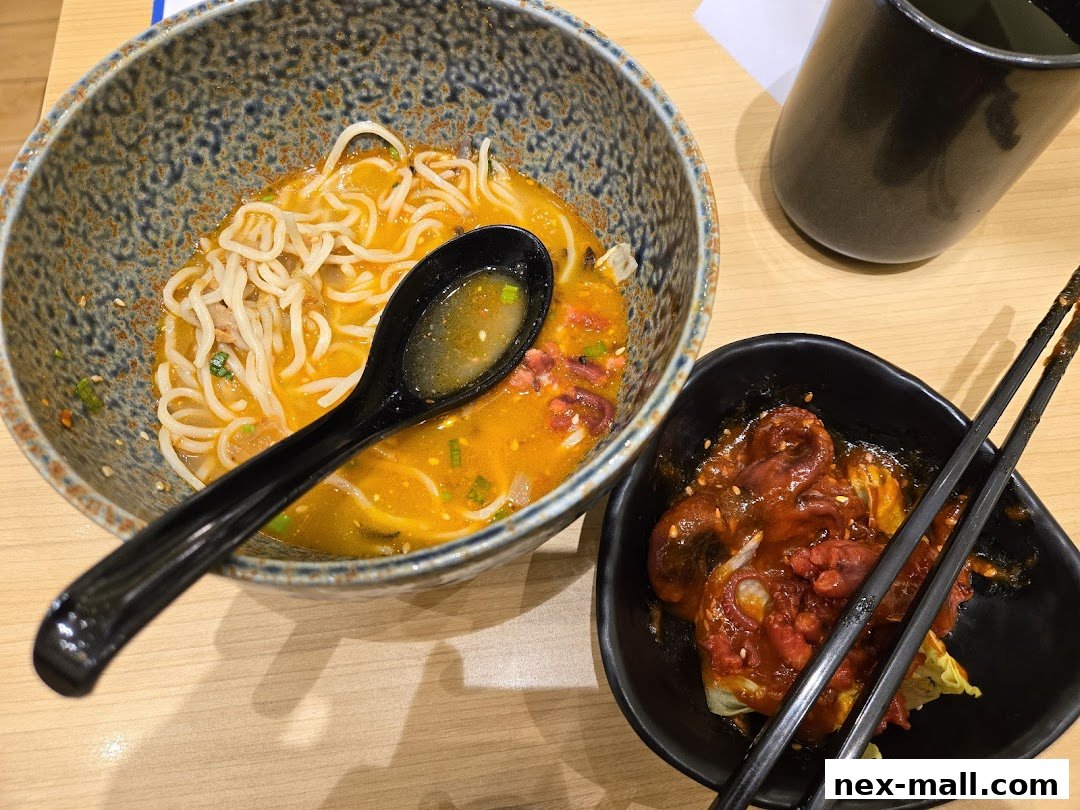 A close-up of a bowl of ramen and a side dish of octopus with chopsticks.