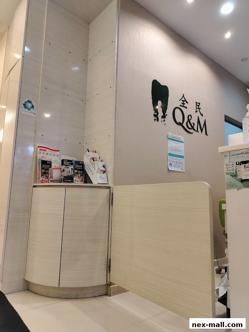 The reception area of Q&M Dental Surgery at NEX, Serangoon, with a logo and brochures.
