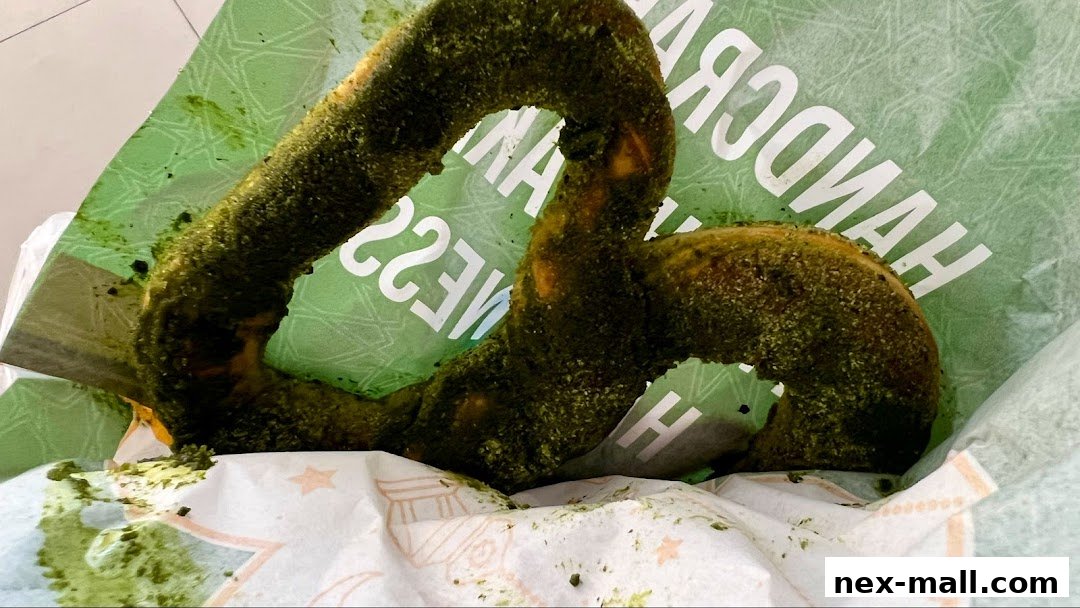 A close-up of a green-dusted pretzel in a paper bag with visible text.