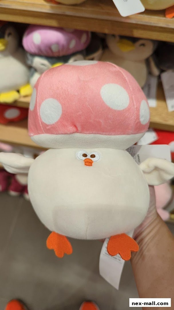 A person holds a cute plush toy with a pink mushroom hat and orange feet.