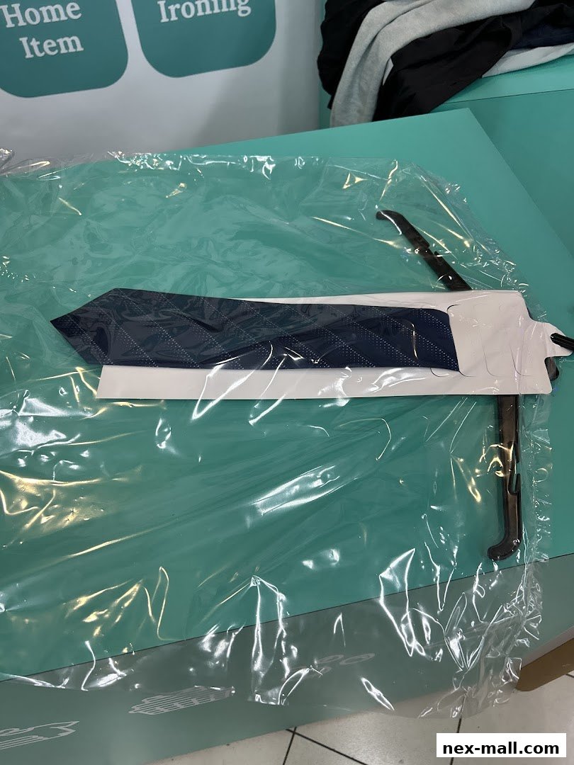 A neatly pressed and packaged navy blue tie with a diamond pattern on a hanger.