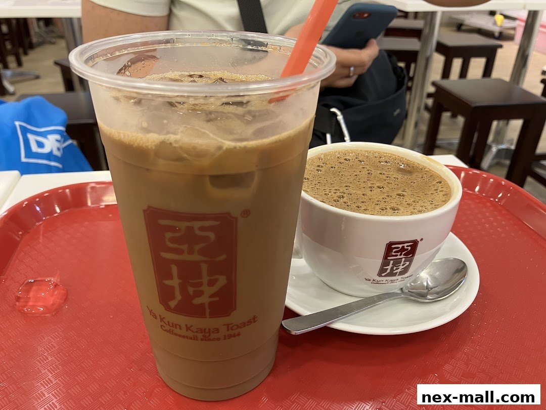 A close-up of two beverages from Ya Kun Kaya Toast, one in a plastic cup and the other in a ceramic mug.