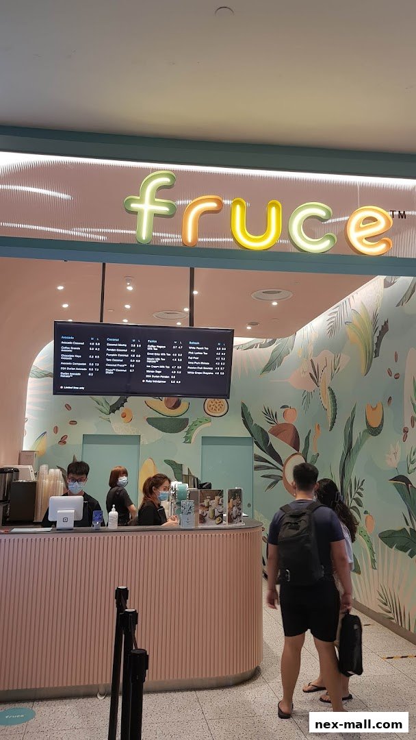 A brightly lit juice bar with a colorful fruit-themed mural and a digital menu board.