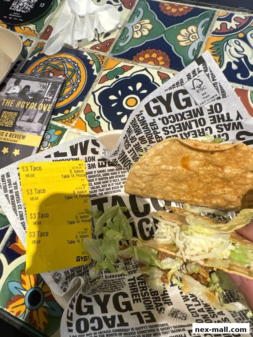 A close-up of Guzman y Gomez tacos and wrappers on a colorful tiled surface.