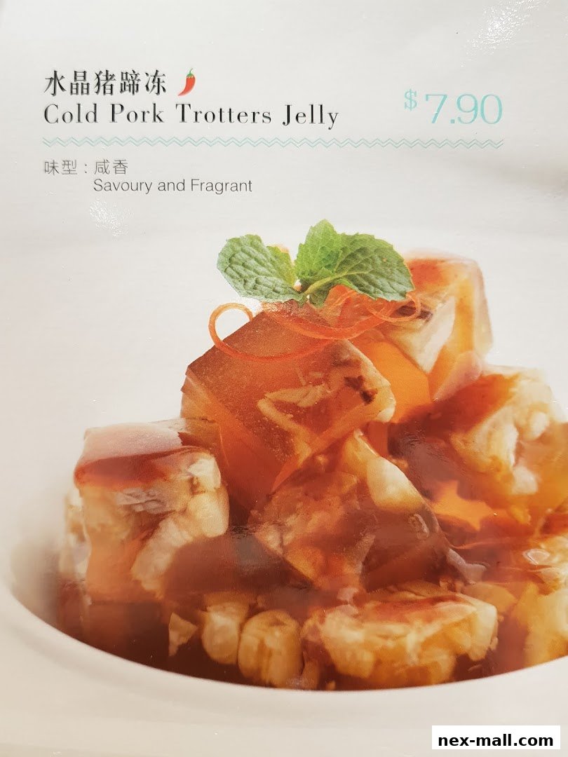 A close-up of Cold Pork Trotters Jelly with mint garnish and sauce.