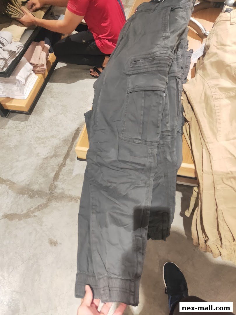 A person is browsing through cargo pants displayed in a retail store.