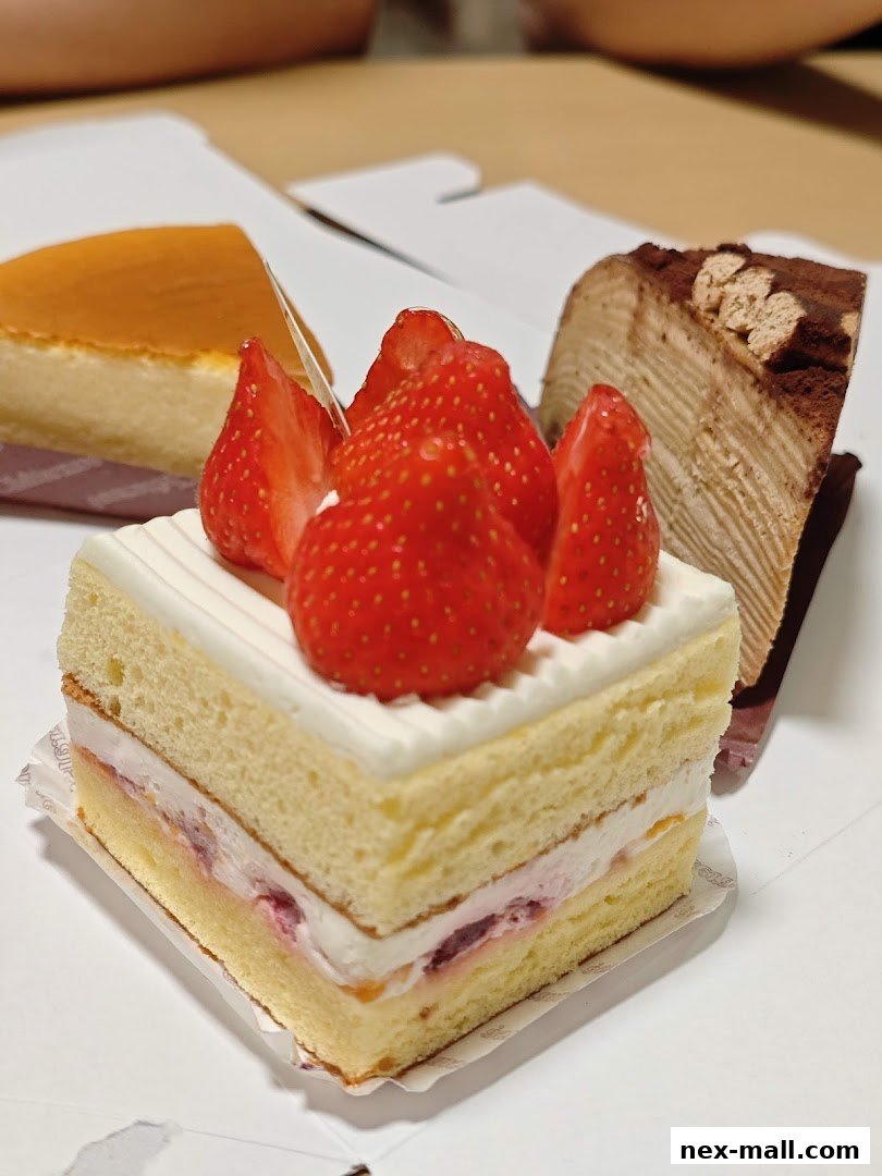 A close-up shot of three delicious-looking cakes, one topped with fresh strawberries.