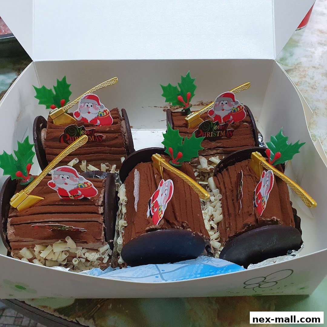 A box of six chocolate log cakes decorated with Santa Claus and Christmas holly.