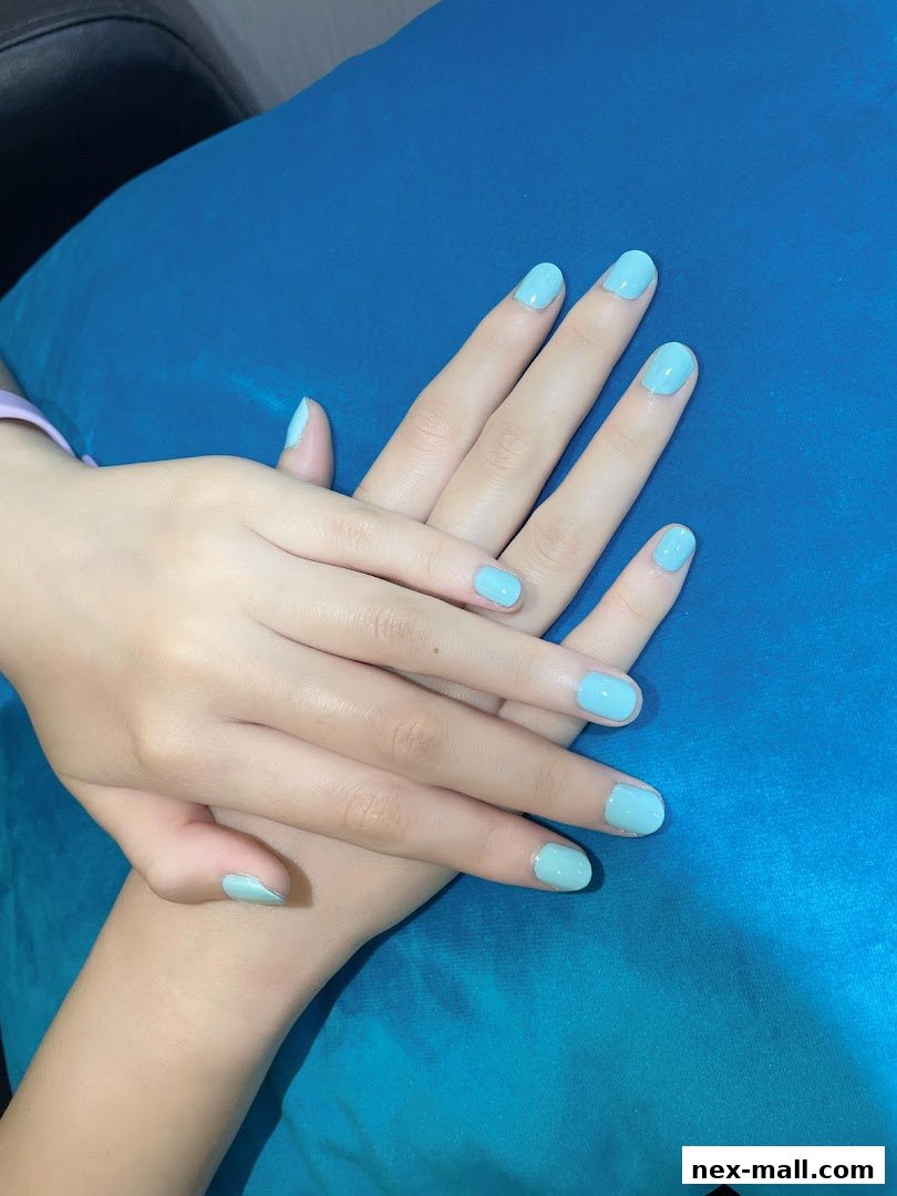 A close-up shot of a person's hands with freshly painted light blue nails.
