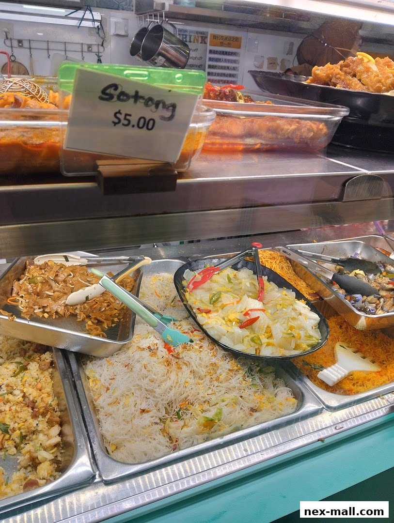 A display of various Asian dishes, including noodles and fried items, at a food stall.