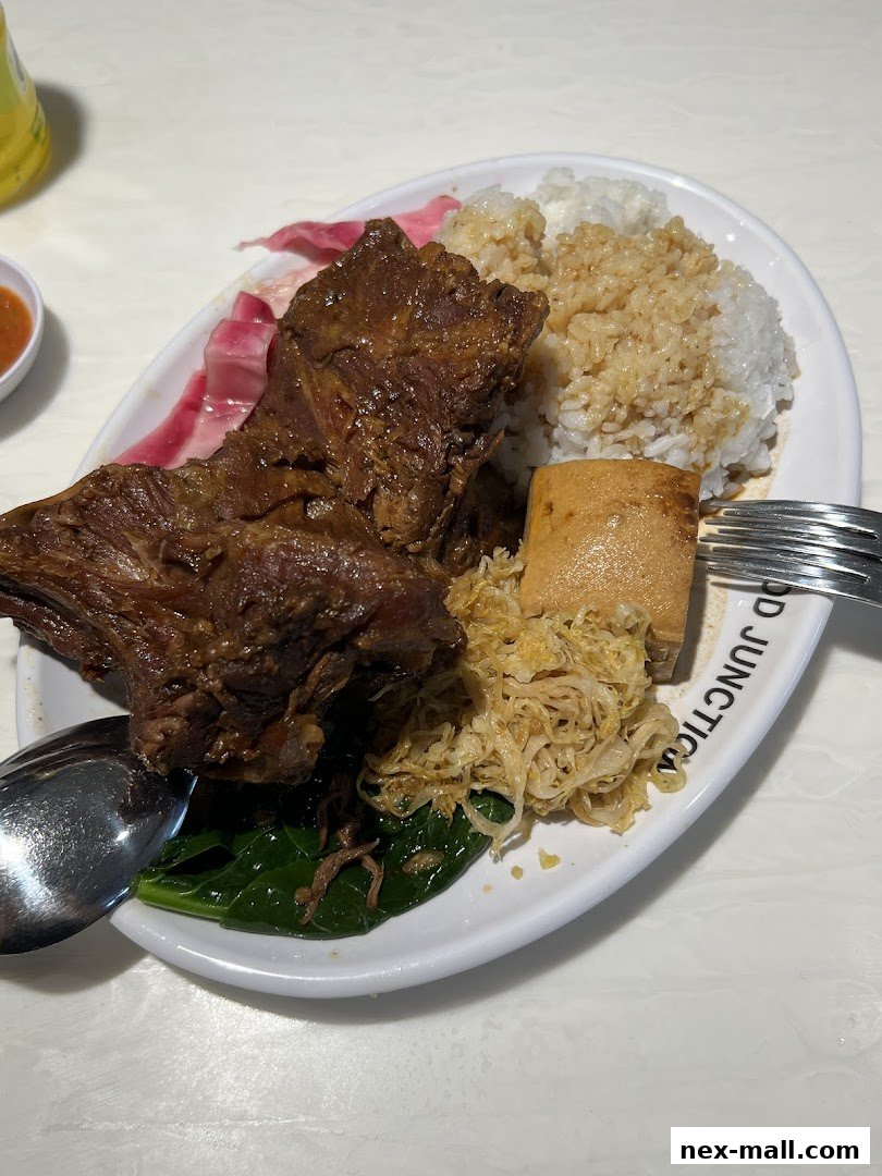 A plate of braised pork ribs with rice, tofu, and vegetables.