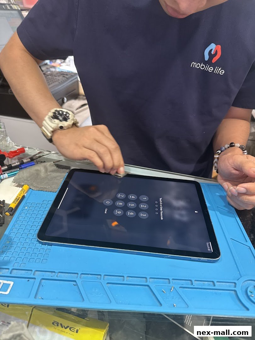 A technician is repairing an iPad, showing the passcode screen and the Mobile Life logo.