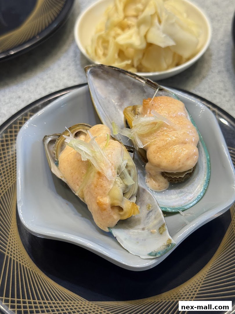 Two mussels topped with creamy sauce and garnished with green onions, served in a grey dish.