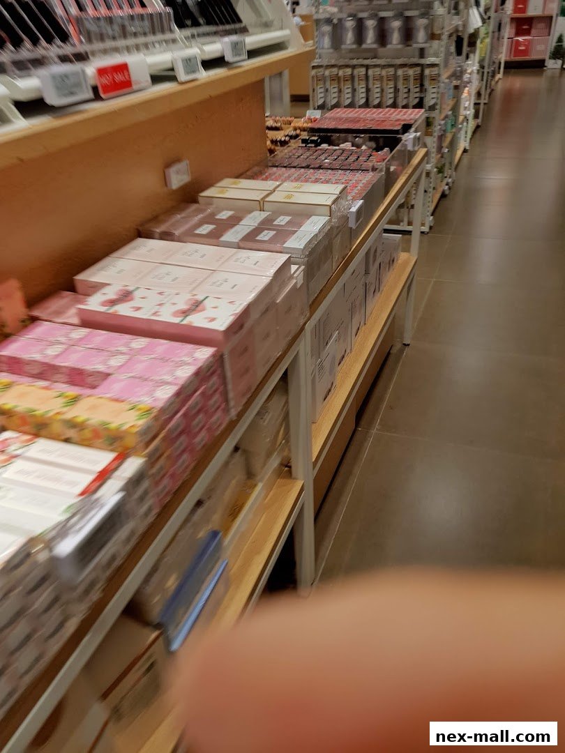 A retail store aisle displaying various packaged goods, likely cosmetics or stationery, on shelves.