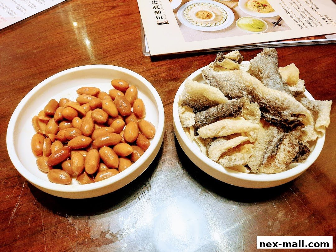 Two bowls of appetizers, one with peanuts and the other with crispy fish skin, are placed on a wooden table.