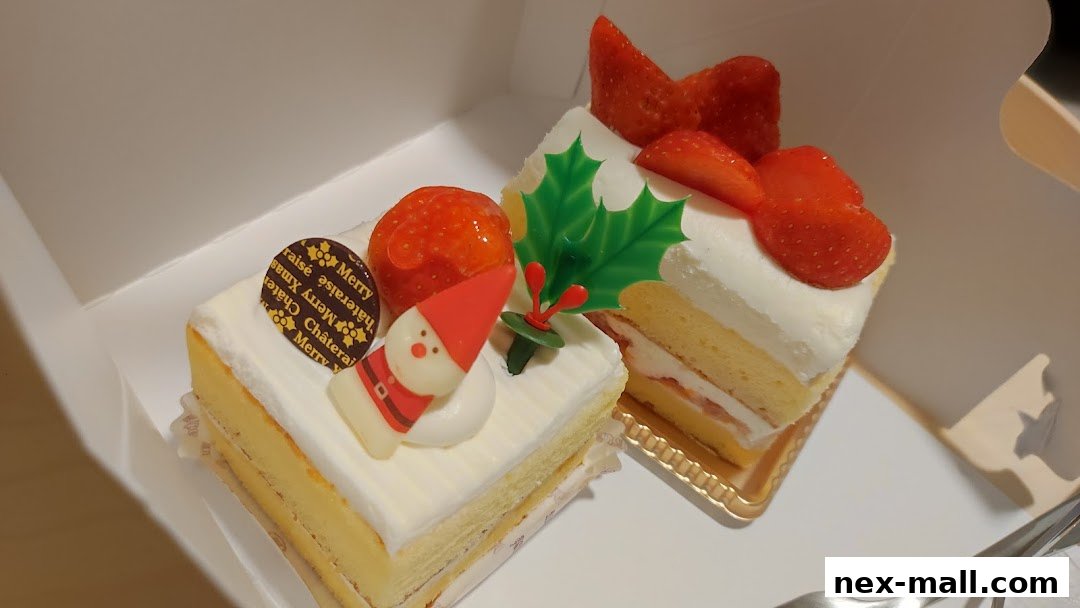 Two slices of festive Christmas cake with strawberries and Santa decorations.
