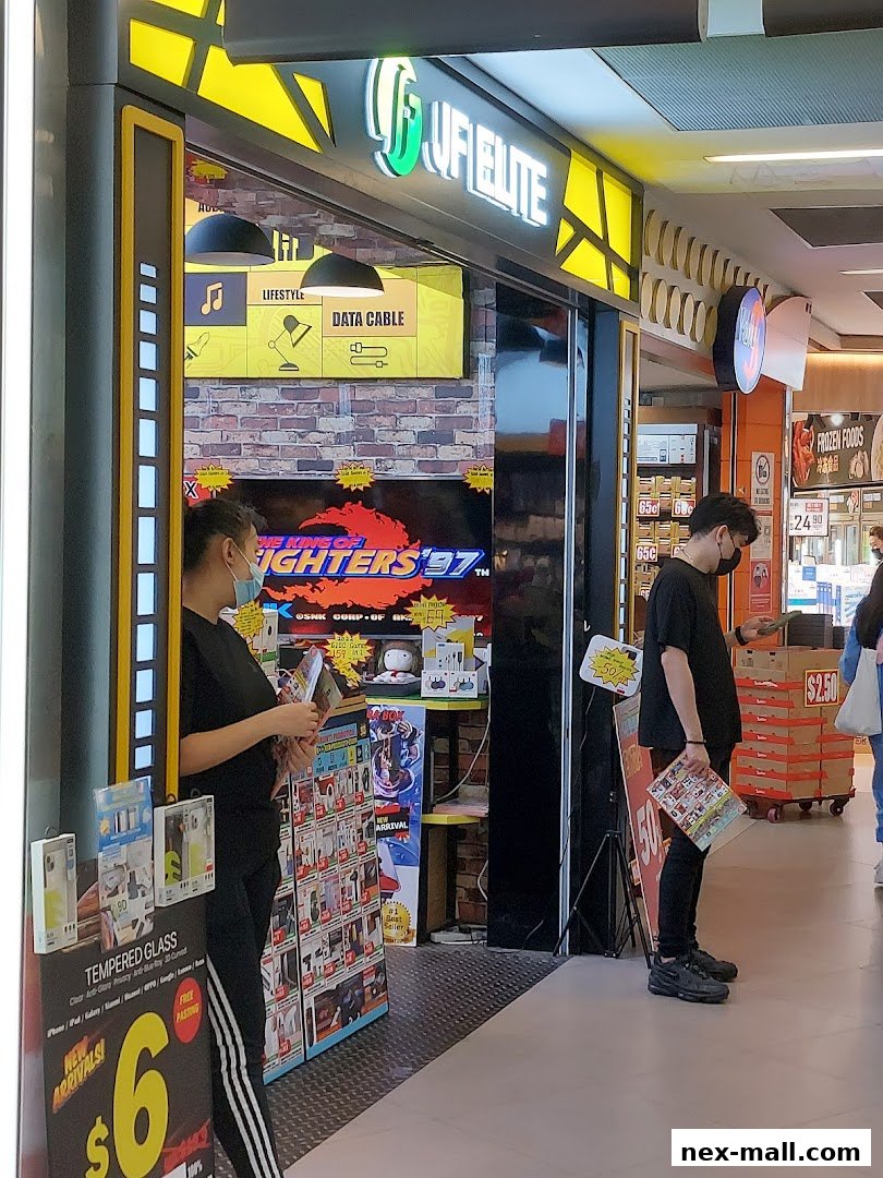 Shop front of JF Elite NEX, showcasing electronics and accessories with promotional signage.