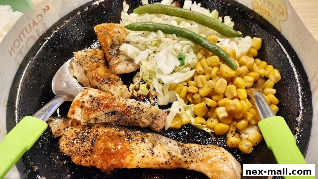 A sizzling hot plate of grilled chicken with corn, cabbage, and green beans.