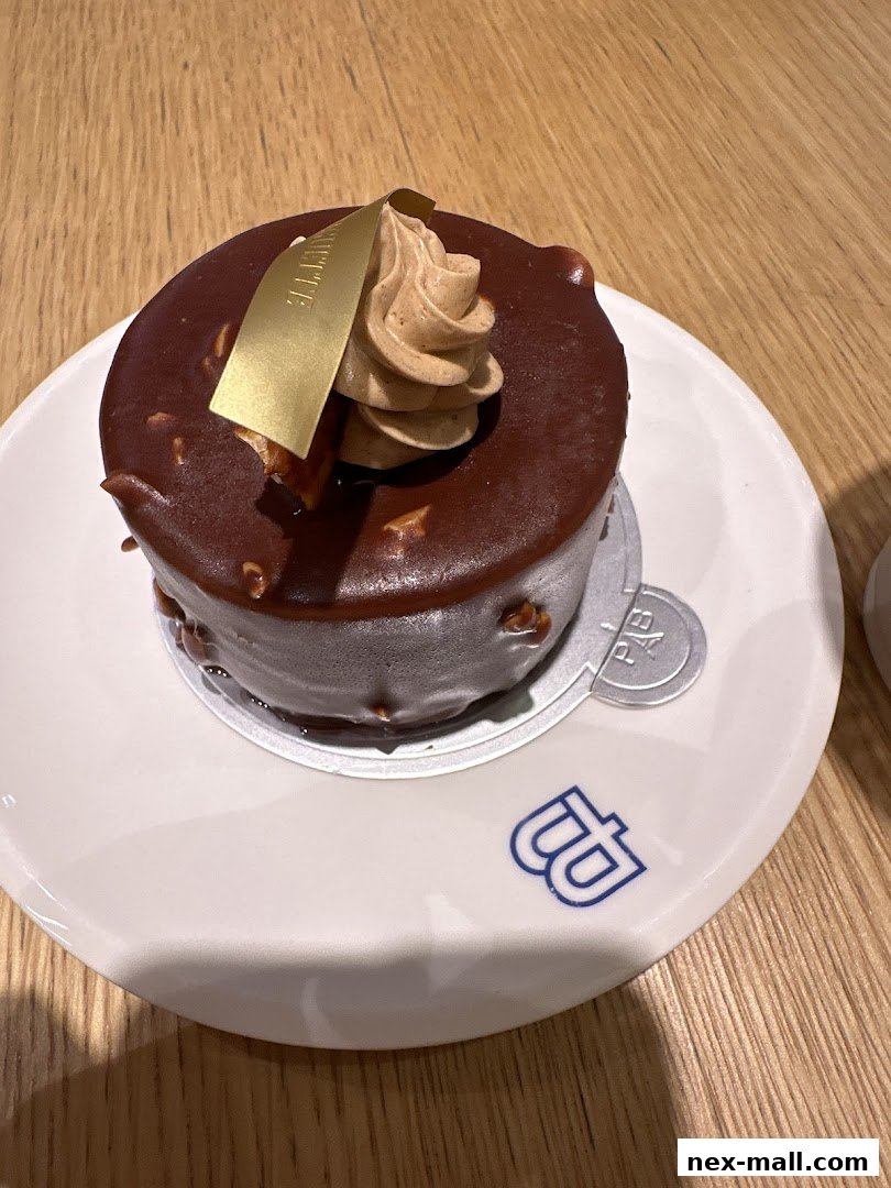 A close-up of a chocolate cake with a swirl of cream and a gold accent.