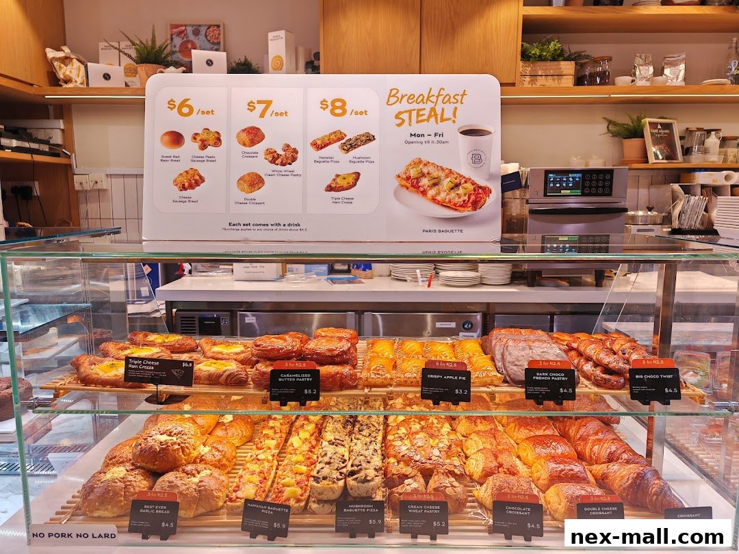 A display case filled with various pastries and breads at Paris Baguette NEX.