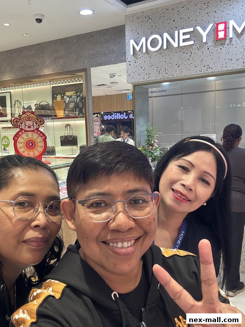 Three smiling women pose for a selfie in front of a MoneyMax Pawnshop.