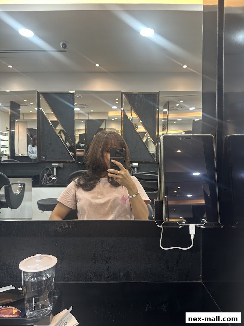 A person takes a mirror selfie in a modern hair salon, showing off their new haircut.