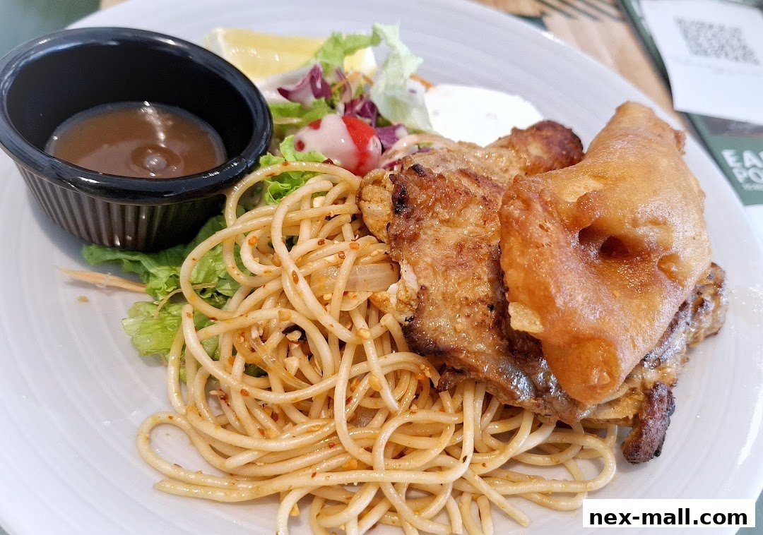 A plate of grilled chicken with spaghetti, salad, and dipping sauce.