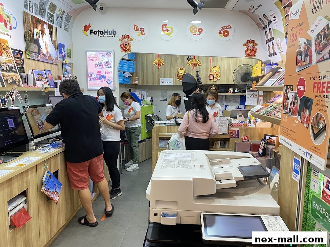 Customers and staff inside a FotoHub store, with printing equipment and photo displays.